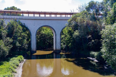 Bridge over river in forest against sky