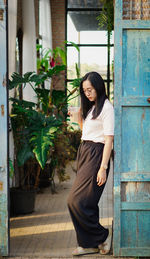 Portrait of young woman standing against wall