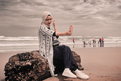 People sitting on beach by sea against sky