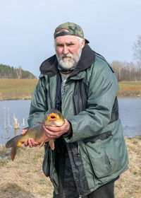 A fisherman on the shore of a lake, carp caught in the hands of a fisherman, amateur carp fishing