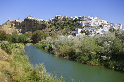 Scenic view of river and buildings against clear sky