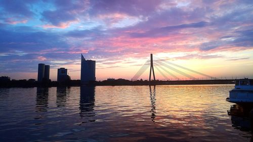 Silhouette bridge over river against sky during sunset