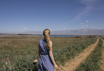 Woman walking on field against sky