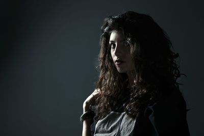 Close-up of young woman against black background