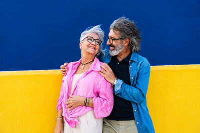 Portrait of smiling couple standing against wall