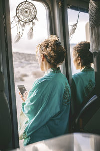 Rear view of woman looking through window