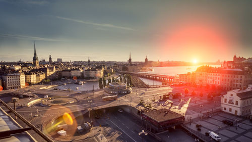 Aerial view of cityscape and river against sky during sunset 