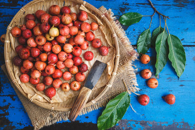 High angle view of figs in wicker basket with knife on wooden table