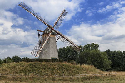 Traditional windmill on field against sky