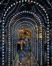 Rear view of woman walking in illuminated city at night