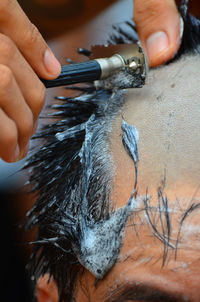 Cropped hand of man shaving person head