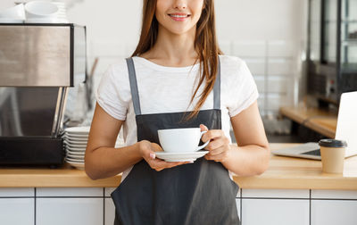 Midsection of woman holding coffee cup