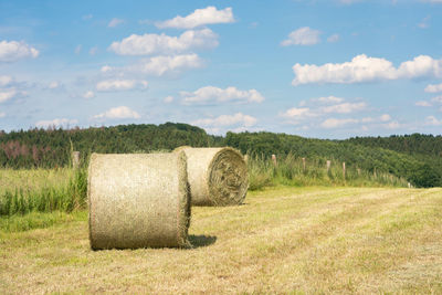 Hay bales on field against sky