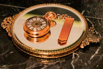 Close-up high angle view of pocket watch on mirror