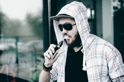 Close-up of young man smoking electronic cigarette