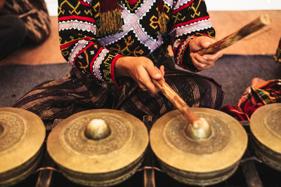 Midsection of woman playing traditional musical equipment