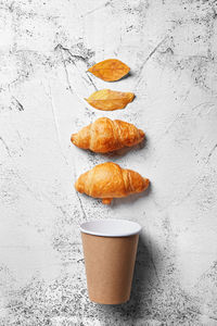 Close-up of autumn leaves with croissants and disposable cup on table