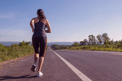 Full length of woman walking on road against sky