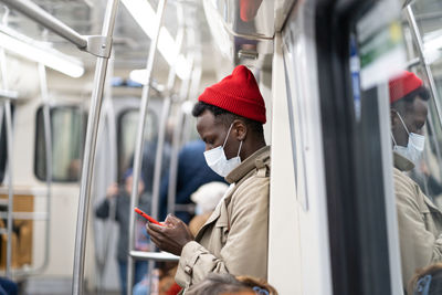 Man wearing mask using mobile phone in train