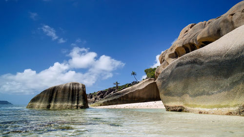 Rock formations by sea against blue sky