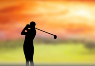 Silhouette person standing on golf course against sky during sunset