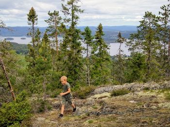 Full length of a boy in forest against sky