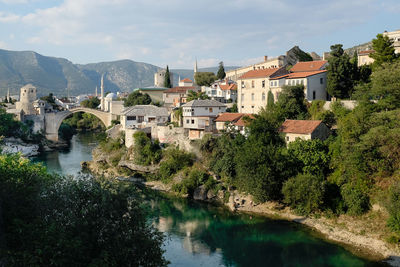 River amidst houses and trees against sky