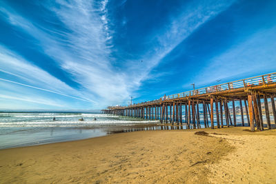 Pier on beach against blue sky