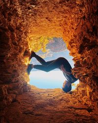 Upside down image of man amidst rock formation against sky