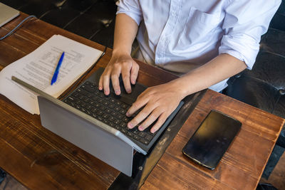 Midsection of man using laptop at table