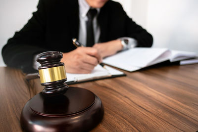 Midsection of man holding glass while sitting on table