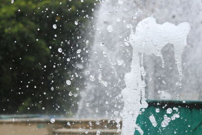 Close-up of water drops on window against sky