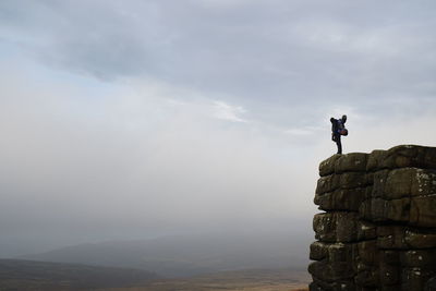 Man standing on rock against sky