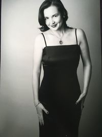 Portrait of smiling woman in dress against gray background