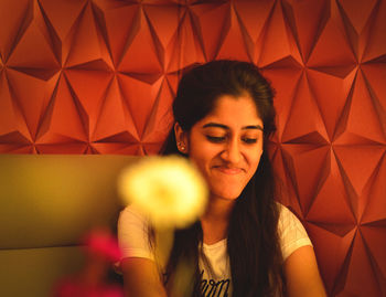 Smiling young woman sitting against patterned wall