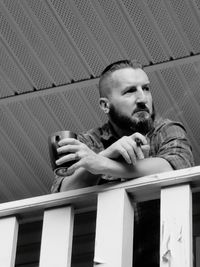 Low angle view of mature man holding coffee cup and cigar