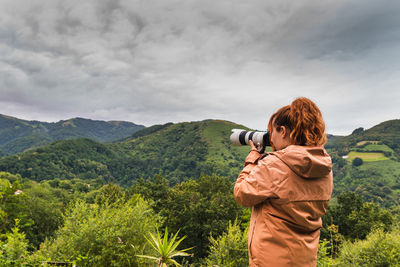 Young unrecognizable woman taking photos in the middle of the mountains in the middle of nature