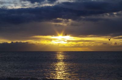 Scenic view of sea against dramatic sky during sunset