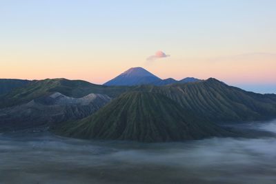 View of bromo and semeru mountains against sky during sunrise. it's savana is covered by the mist.