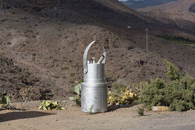Metal structure on field by road against mountains
