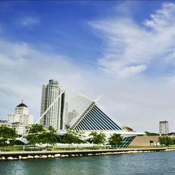 Milwaukee art museum in front of river against cloudy sky