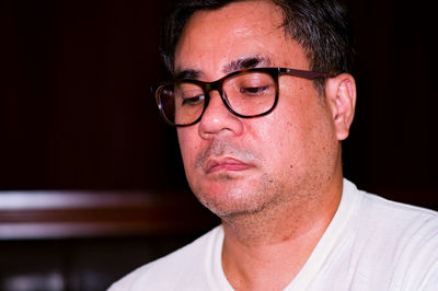 Portrait of man wearing eyeglasses against black background