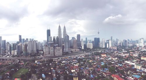 Aerial view of cityscape against cloudy sky