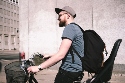 Side view of man carrying backpack while riding bicycle on street