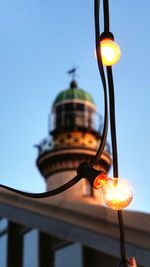 Low angle view of illuminated light bulb against sky