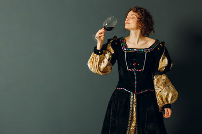 Portrait of woman standing against black background