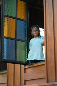 Low angle portrait of smiling girl seen through window