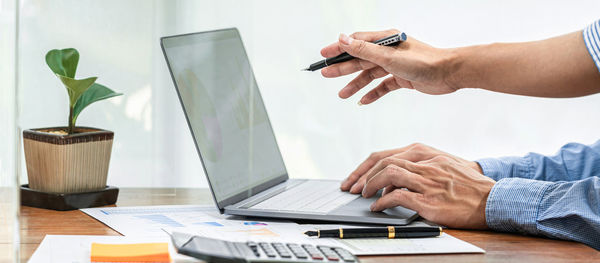 Midsection of man using laptop on table