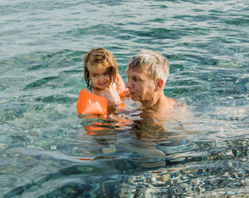 Cute girl with grandfather swimming in sea