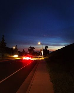 Light trails on road against sky at night